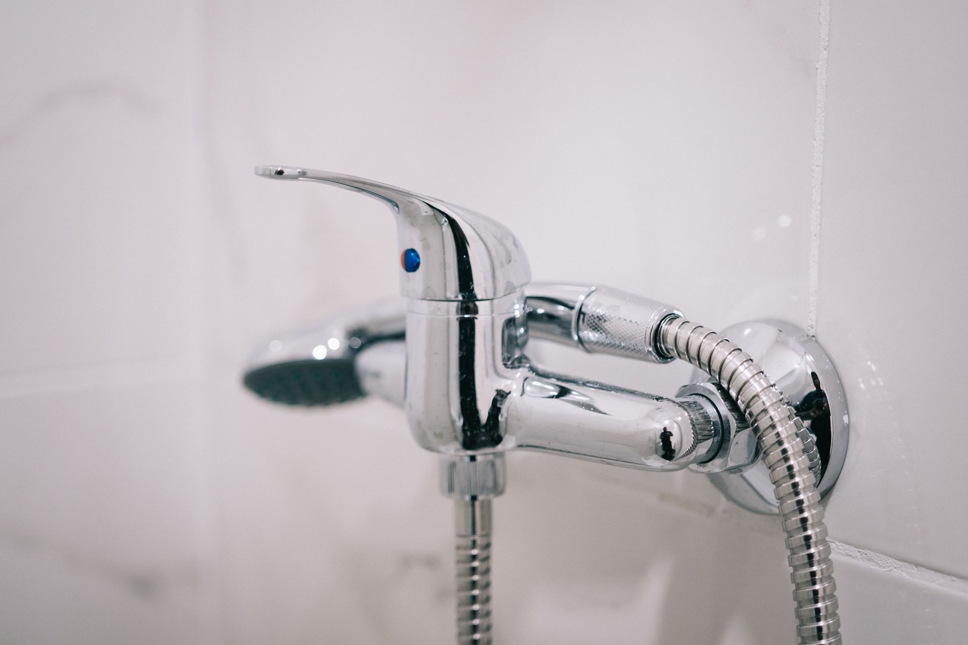 A detailed view of a sleek chrome shower faucet in a clean bathroom setting.